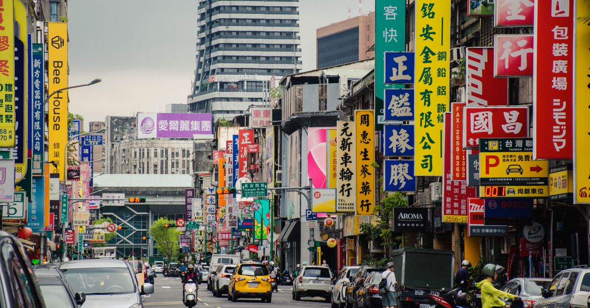Rue animée de Taipei avec des panneaux colorés et un trafic intense, présentant la vie urbaine à Taiwan.