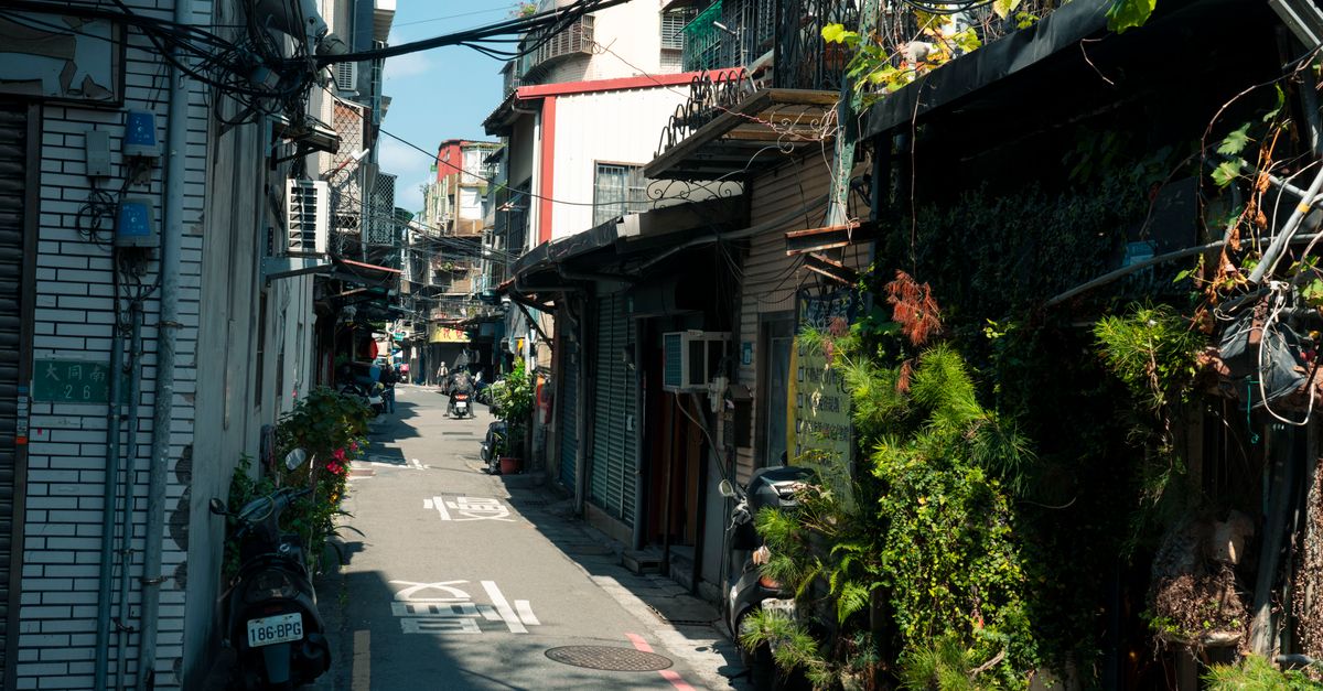 Explorez une ruelle animée de Taipei, à Taïwan, où se mêlent vie urbaine et végétation luxuriante.
